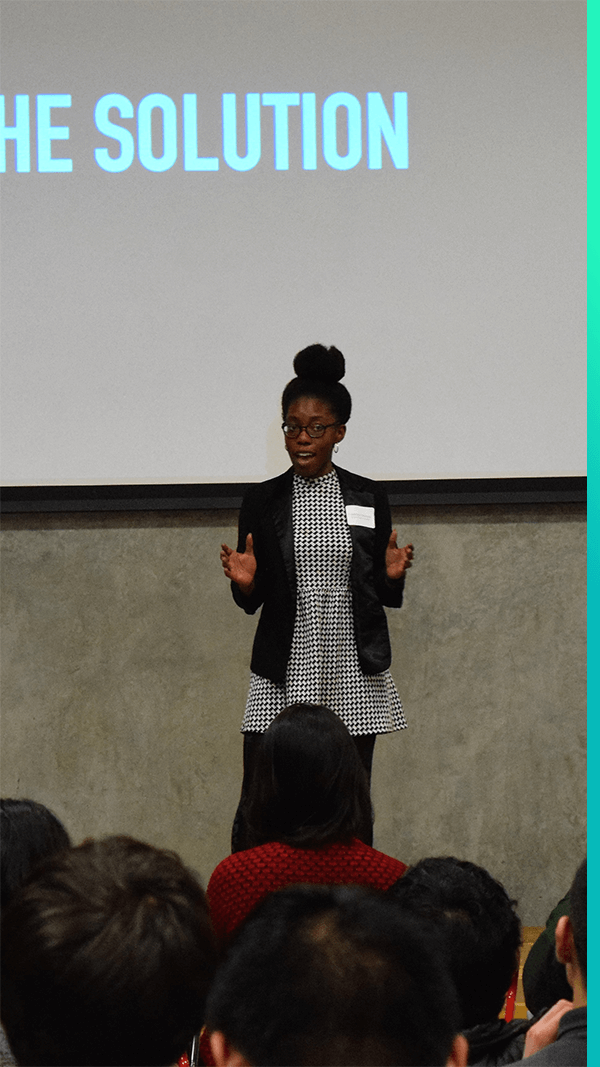 Picture of female student presenting to audience in front of large screen